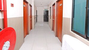 A corridor with doors on both sides, a red trash bin, and a sign indicating an exit. - Hotel O Ayuni Hotel (Bandar Baru Bangi)