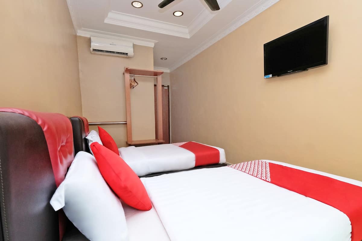 A hotel room with a bed, a TV mounted on the wall, and a mirror.