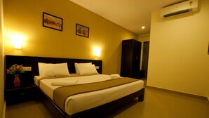 Habitación de hotel con cama, mesitas de noche, un jarrón de flores y dos luces fijadas a la pared.