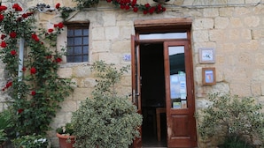 A stone building with a wooden door, numbered 26, and potted plants outside. - Locanda di Cadì (Petralia Soprana)