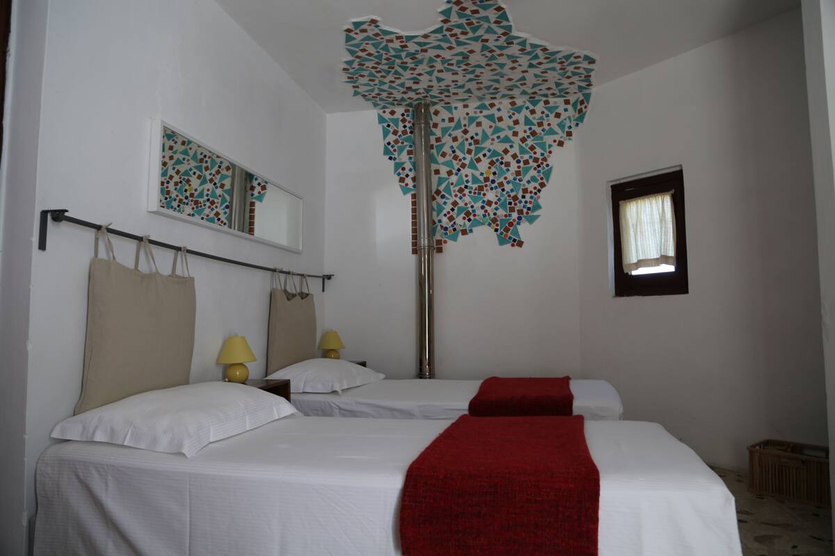 A hotel room with two beds, a large mirror, a decorative ceiling, and a small window.