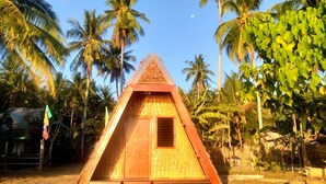 A triangular wooden structure with a window, surrounded by palm trees and a clear sky. - La Acuario Beach Inn (San Vicente)