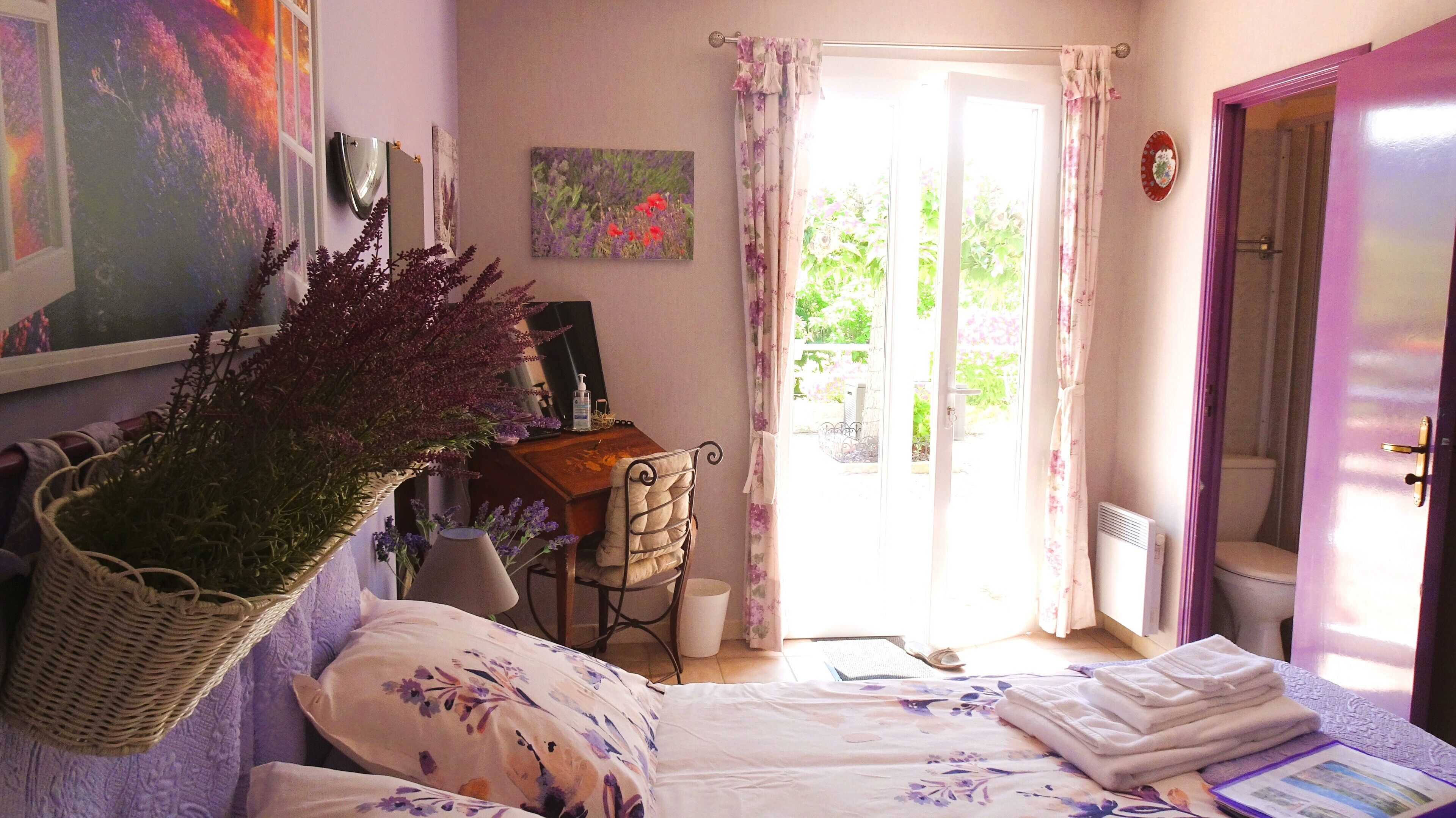 Un dormitorio con cama, escritorio, silla, radiador y ventana con cortinas.