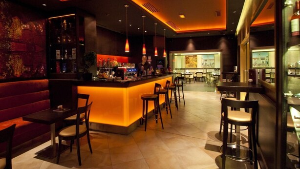 A bar area with a counter, seating, and a view of the cityscape. - Villa Amfora (Dubrovnik)