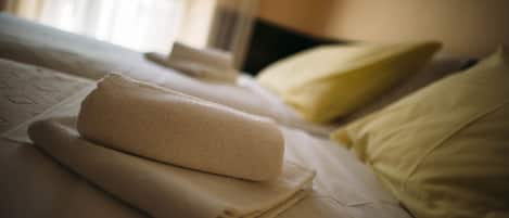 A neatly made bed with a folded towel and pillows.