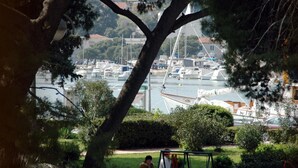 A marina with boats docked, surrounded by greenery and a swing set. - Villa Amfora (Dubrovnik)