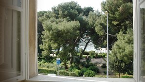 A window view of a park with trees, a playground, and a marina in the background. - Villa Amfora (Dubrovnik)