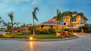Un hotel con un patio espacioso, palmeras y un jardín bien cuidado.
