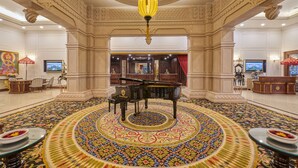 Un vestíbulo imponente con un piano de cola, alfombra decorativa y un candelabro.