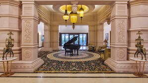 Un vestíbulo imponente con un piano de cola, columnas ornamentadas y una alfombra estampada.