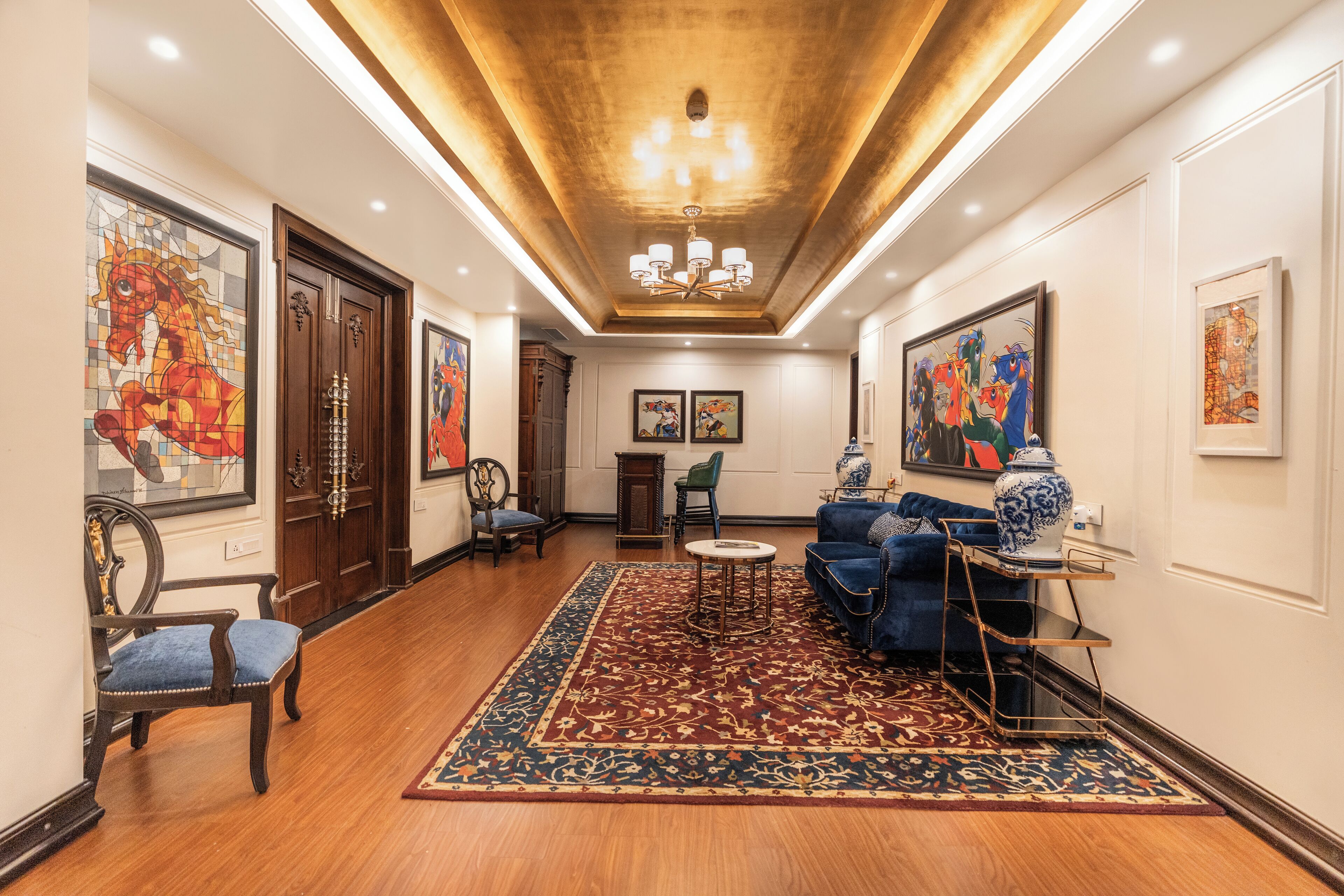 A spacious living room with a wooden floor, a blue sofa, a coffee table, and a patterned rug.