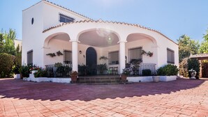 A two-story building with a tiled roof, a central archway, and a paved courtyard. - Alojamiento La Veguilla (Úbeda)