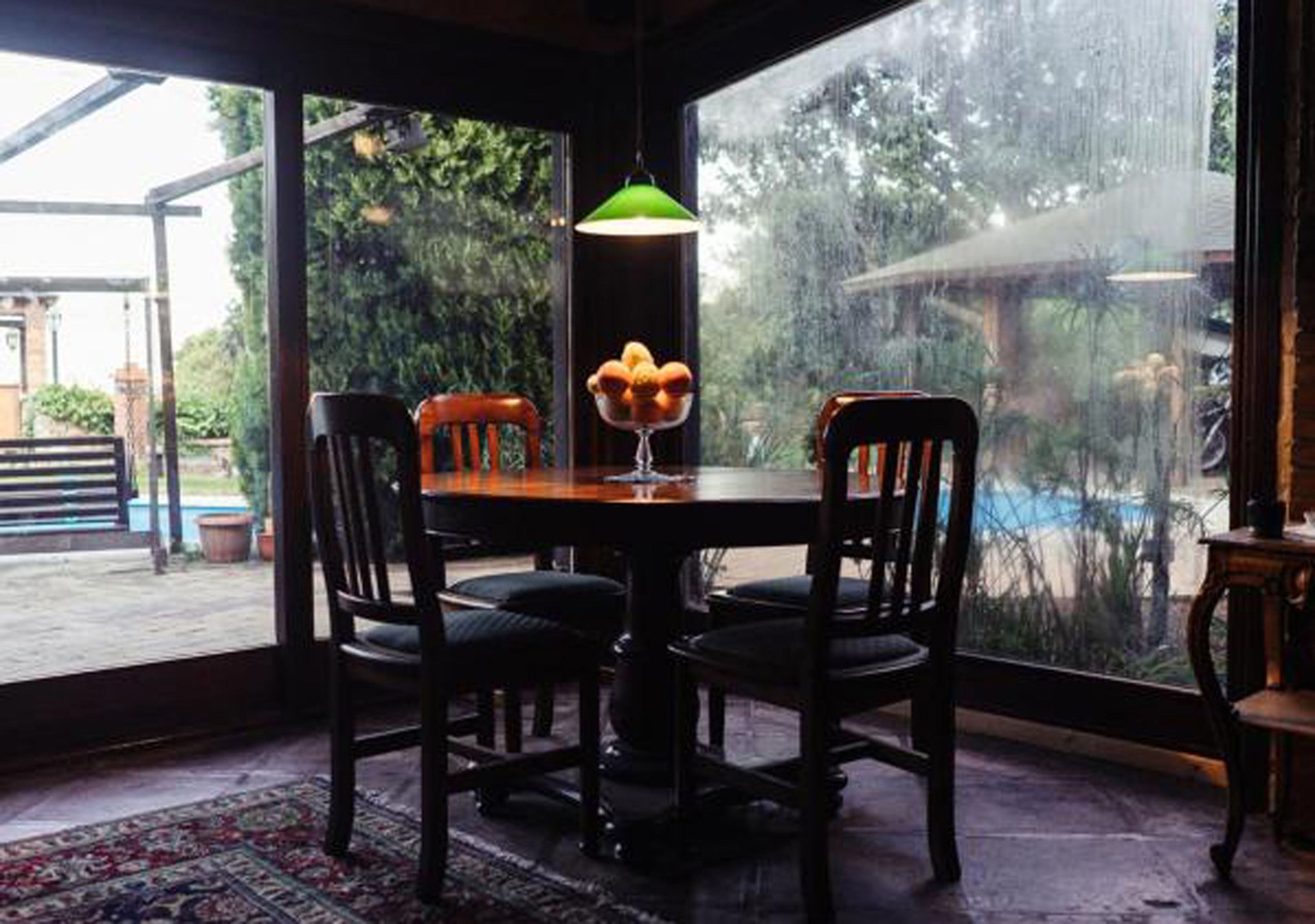 A dining area with a table and chairs, a hanging light fixture, and a view of the outdoors.