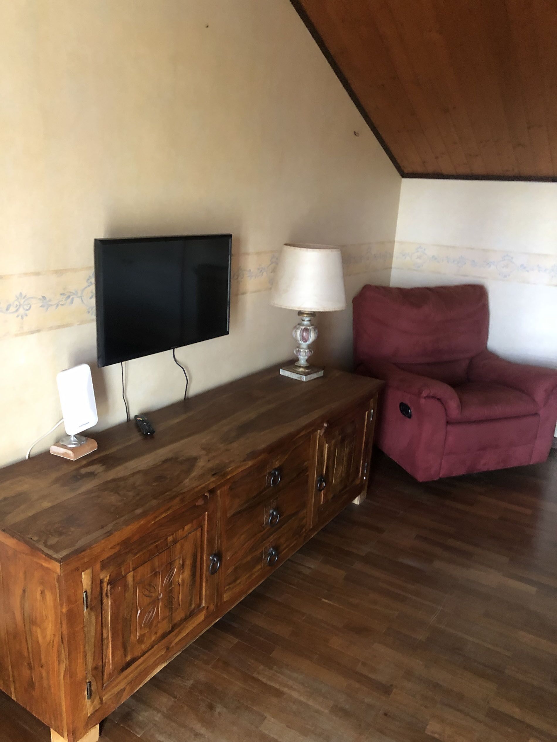 A wooden cabinet with a flat-screen TV, a lamp, and a remote control.