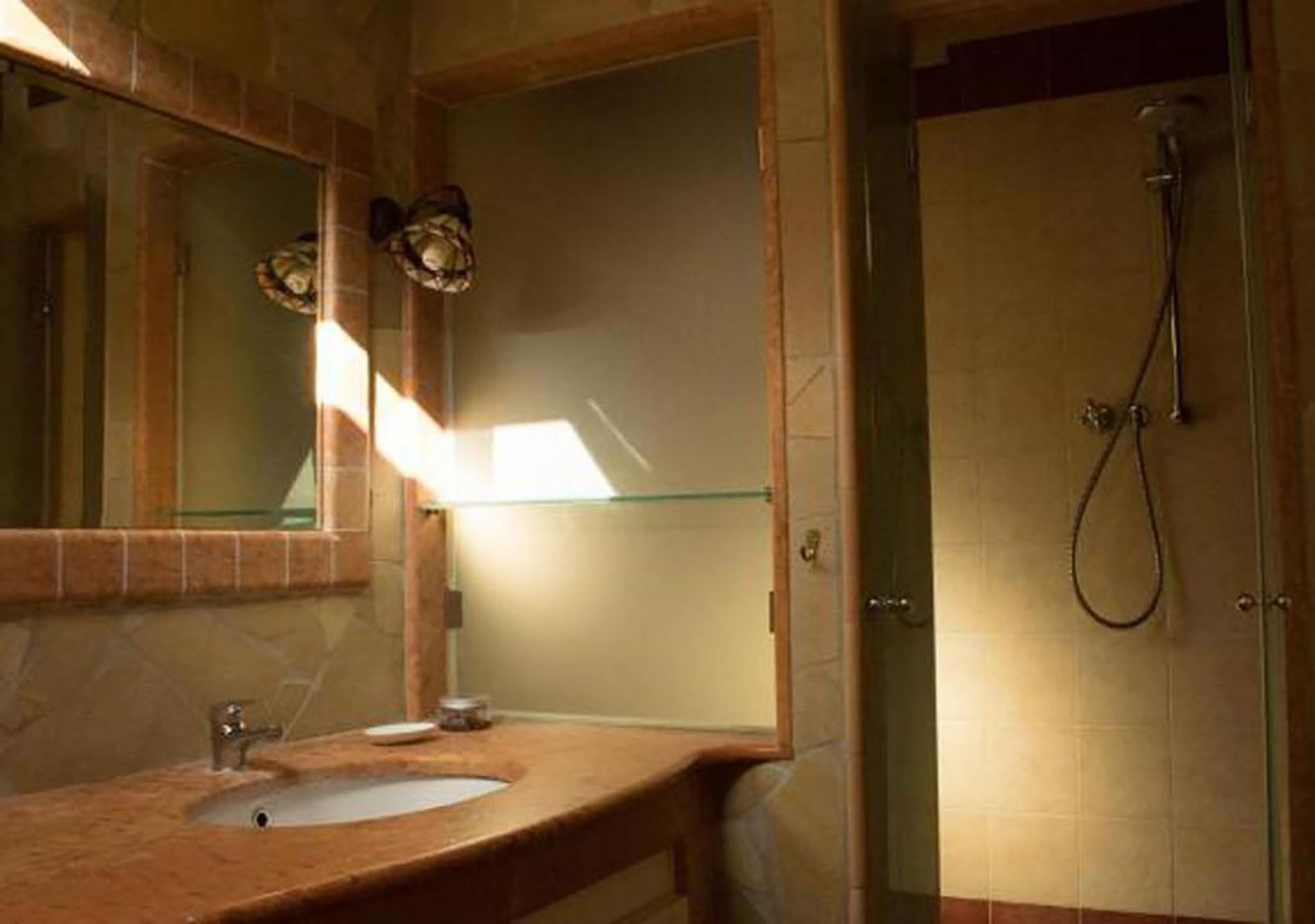 A bathroom with a sink, mirror, and shower.