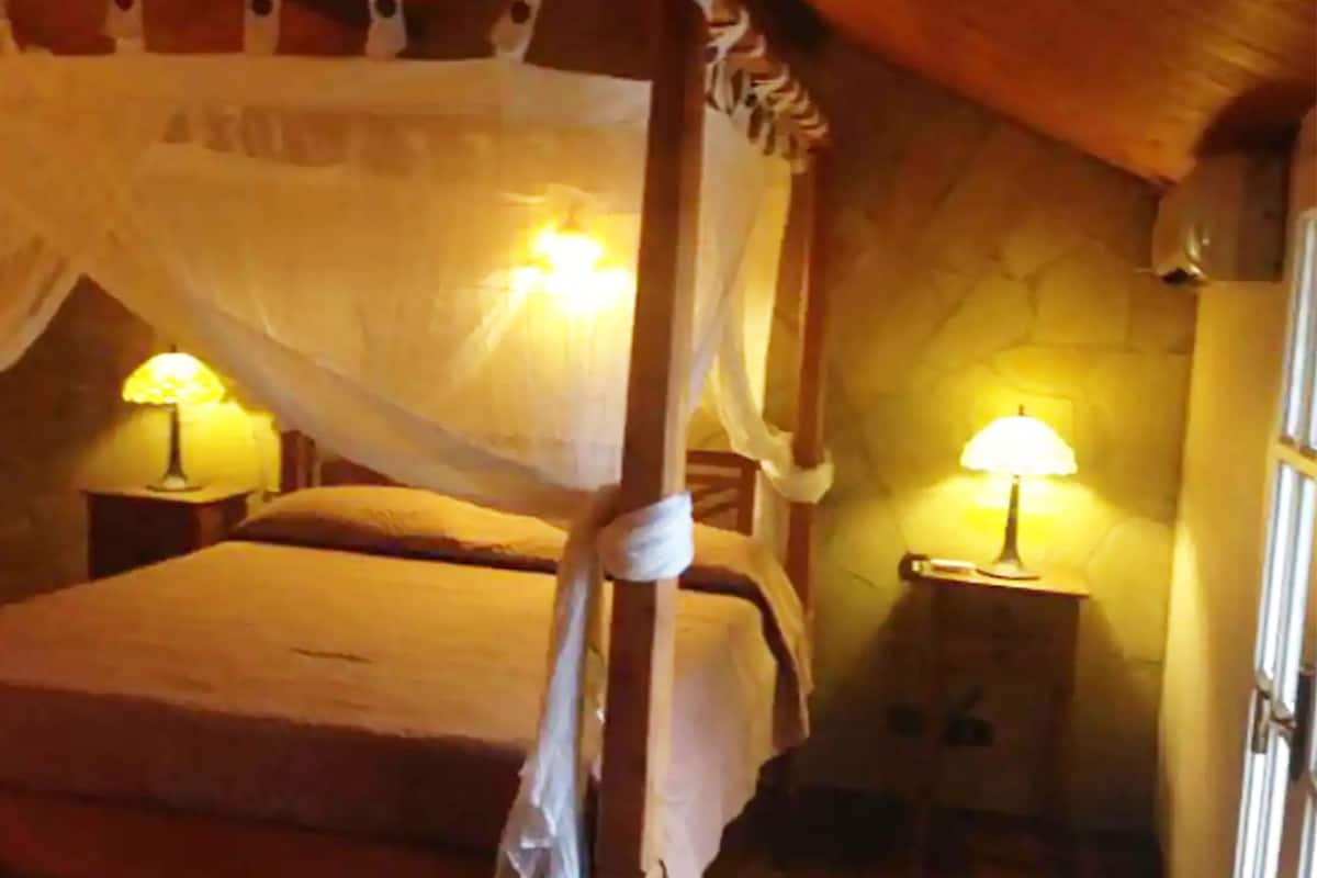 A four-poster bed with a canopy, two bedside lamps, and a wooden headboard.