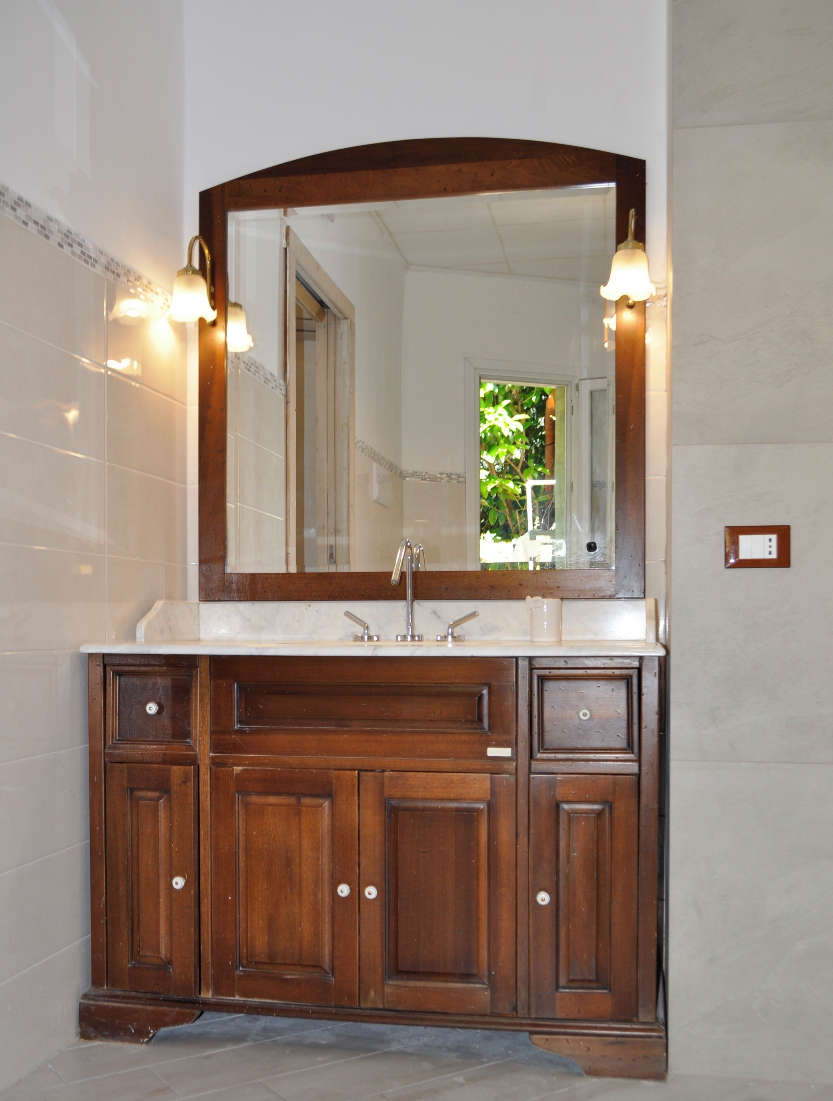 Une salle de bain avec un meuble-lavabo en bois, un grand miroir et deux appliques murales.