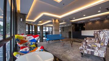 Eine moderne Lobby mit einem blauen Sofa, bunten Stühlen und einem gemusterten Sessel.