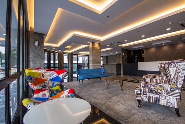 Un hall d’entrée moderne avec un canapé bleu, des chaises colorées et un fauteuil à motifs.