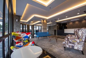 A modern lobby with a blue sofa, colorful chairs, and a patterned armchair.