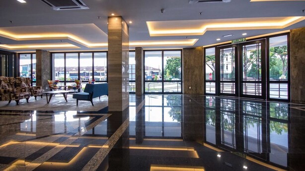 Un vestíbulo moderno con suelo reflectante, ventanas amplias y zonas de estar.