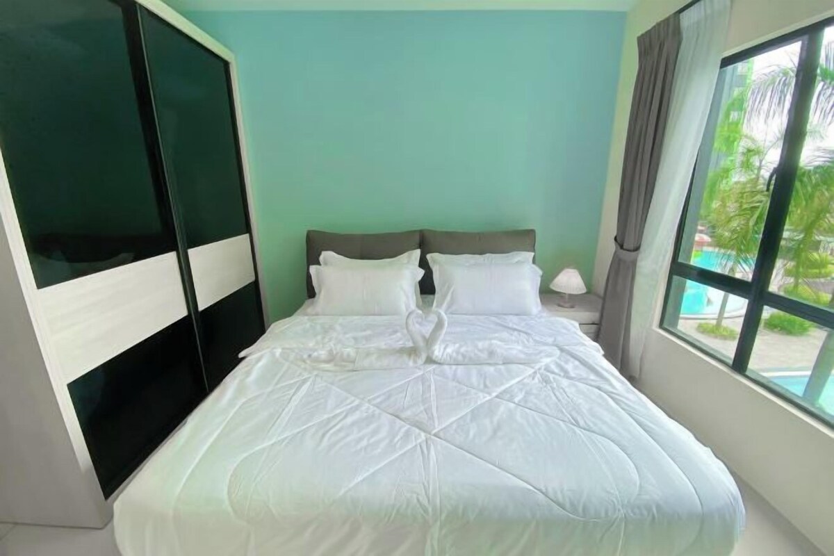 A bedroom with a bed, a nightstand, a window with a view of palm trees, and a sliding door.