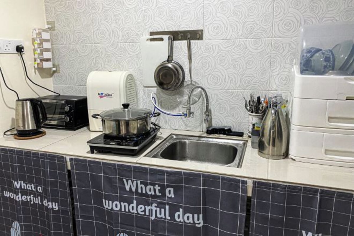Una cocina con estufa a gas, cafetera, hervidor y pileta.