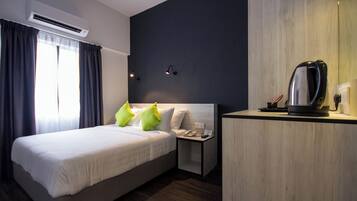 Een hotelkamer met een bed, nachtkastje en koffiezetapparaat.