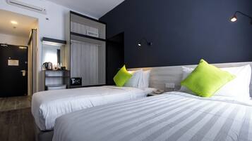 A hotel room with two beds, a wardrobe, a mirror, and a small desk with a lamp.