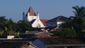 A church with a prominent steeple and a dome, surrounded by residential buildings and palm trees. - Lighthouse Guest (Galle)