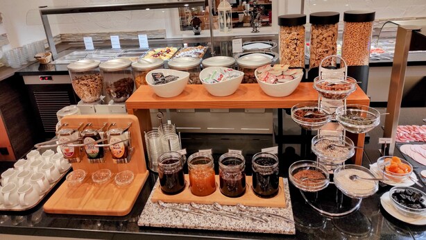 A buffet with various food items and condiments, including jars of spreads, bowls of nuts, and trays of fruits. - Wellness Hotel Garni Krone (Baiersbronn)