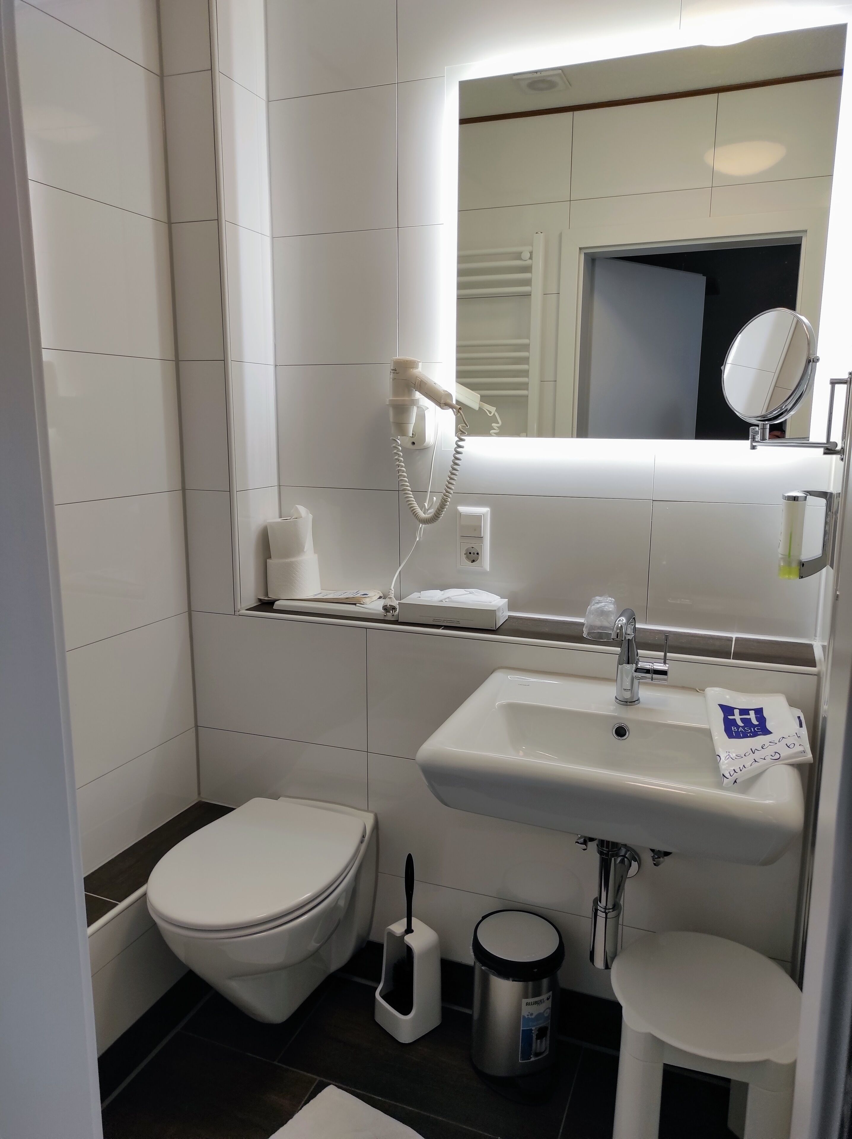 Een moderne badkamer met toilet, wastafel en spiegel.