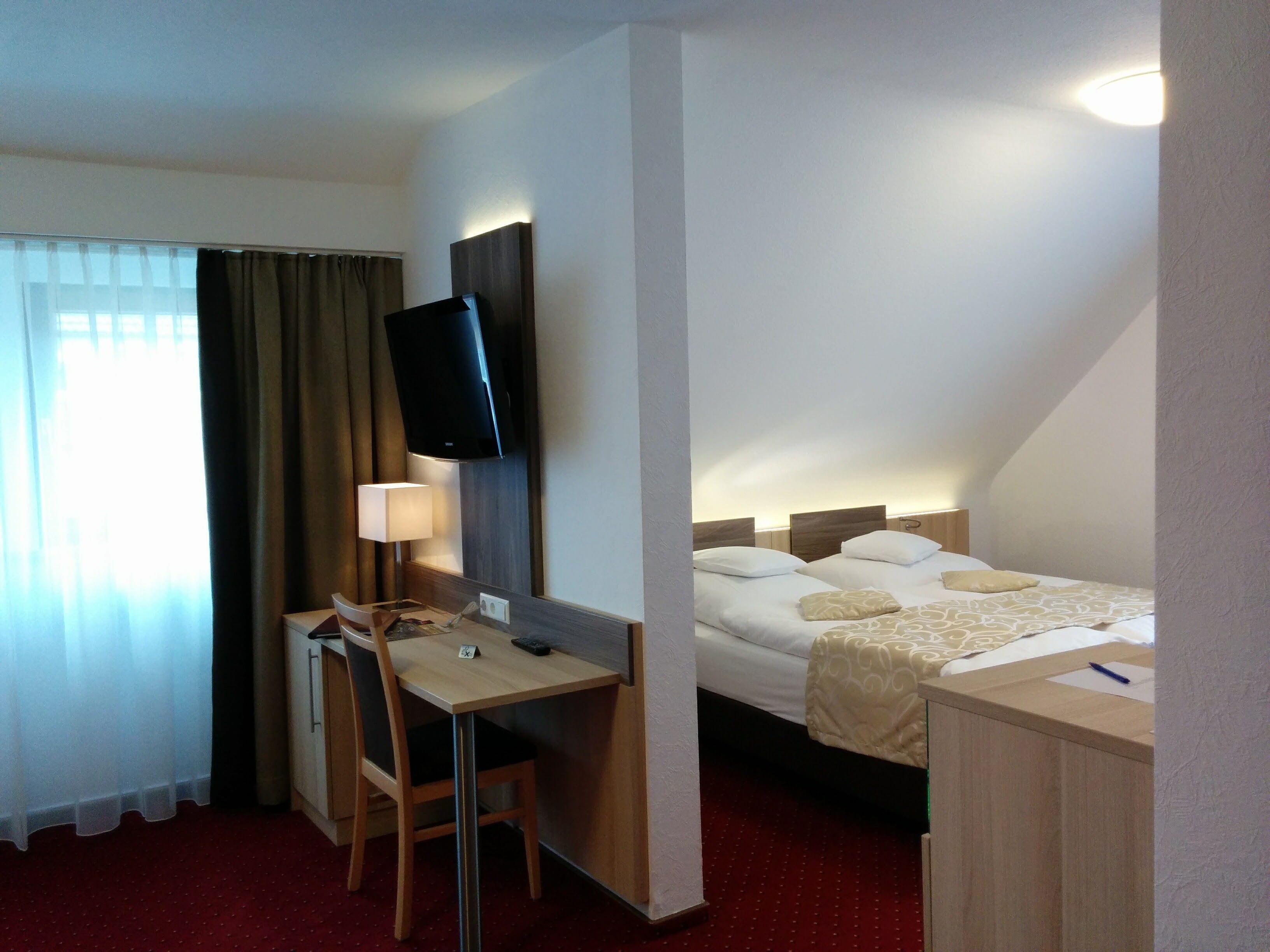 A hotel room with a desk, chair, and two beds.