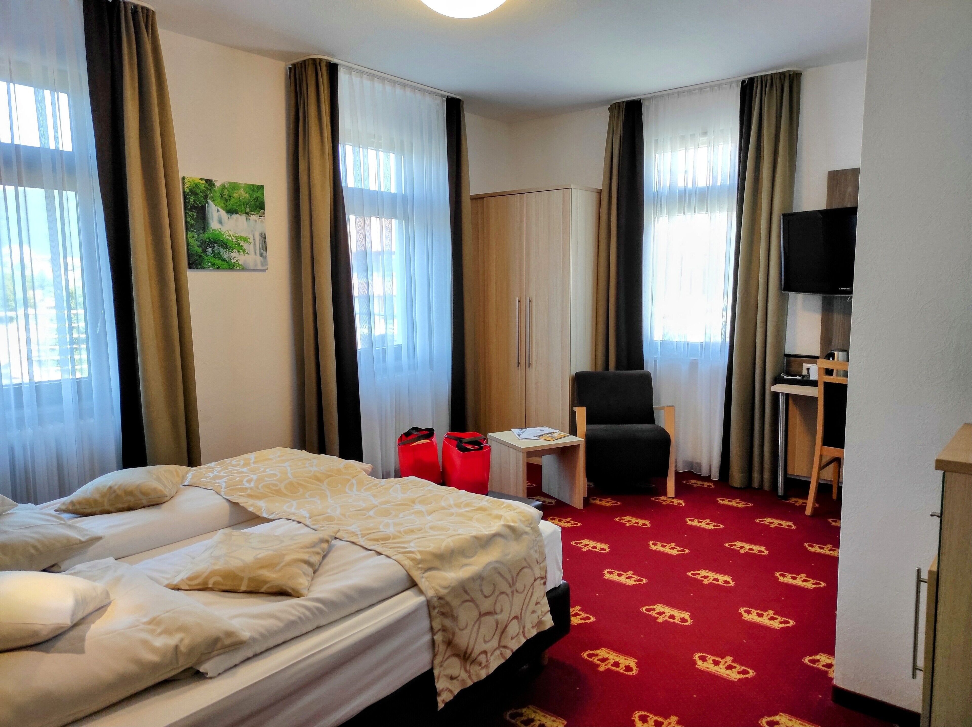 A hotel room with a bed, a desk, a chair, and a television.