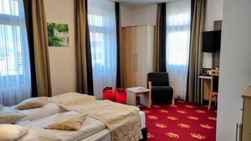 A hotel room with a bed, a desk, a chair, and a television.