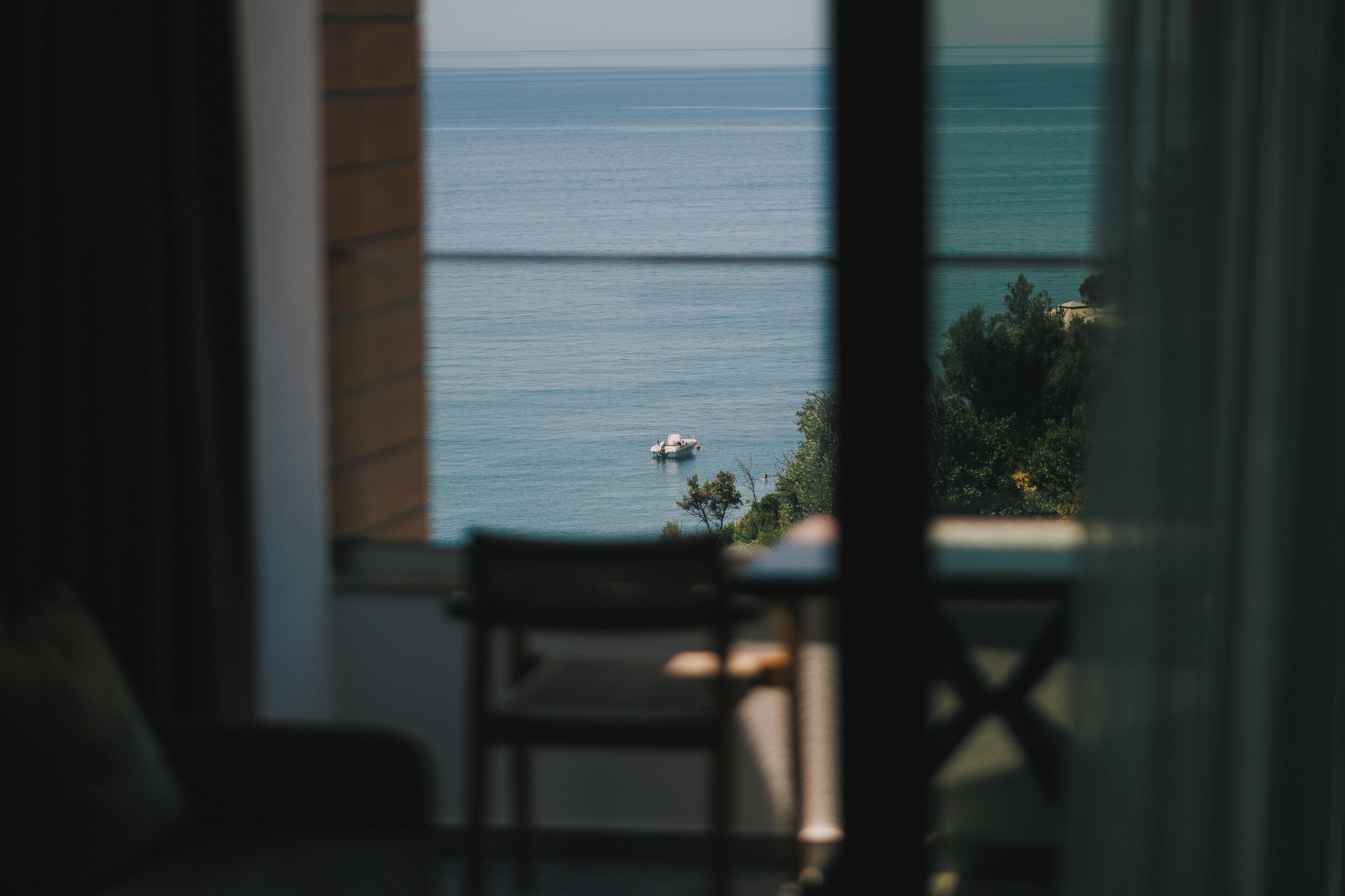 Blick auf das Meer vom Fenster aus, mit einem Stuhl im Raum.
