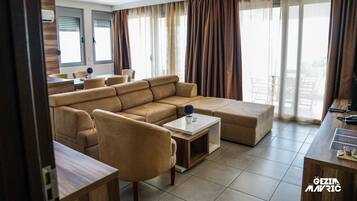 A modern living room with a sectional sofa, a coffee table, and a dining area with chairs.