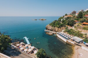 Un complejo turístico costero con aguas cristalinas, un muelle y una costa rocosa.