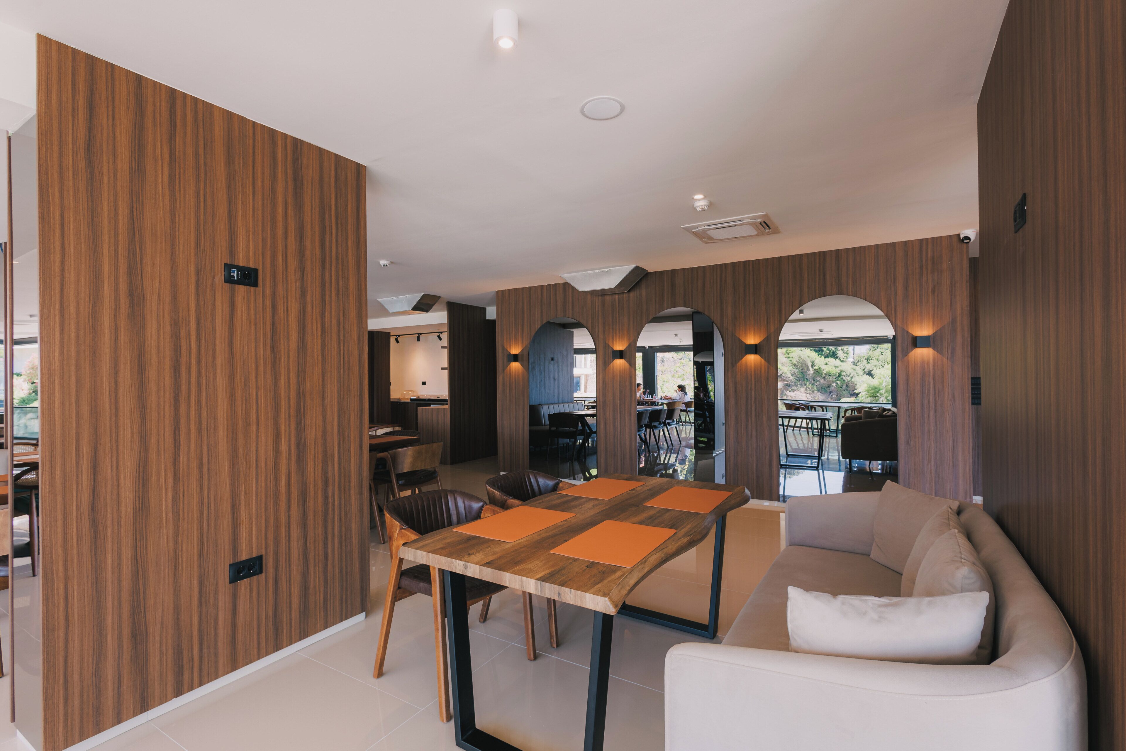 A modern interior with a wooden accent wall, a dining area with a table and chairs, and a seating area with a sofa.