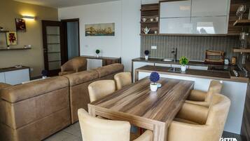 A modern living room with a wooden dining table and beige sofas.