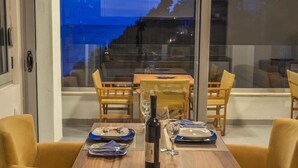 A dining area with a table set for two, a bottle of wine, and a view of the sea through large windows. - HOTEL MEDITERRANEO LIMAN free private beach for hotel guest (Ulcinj)
