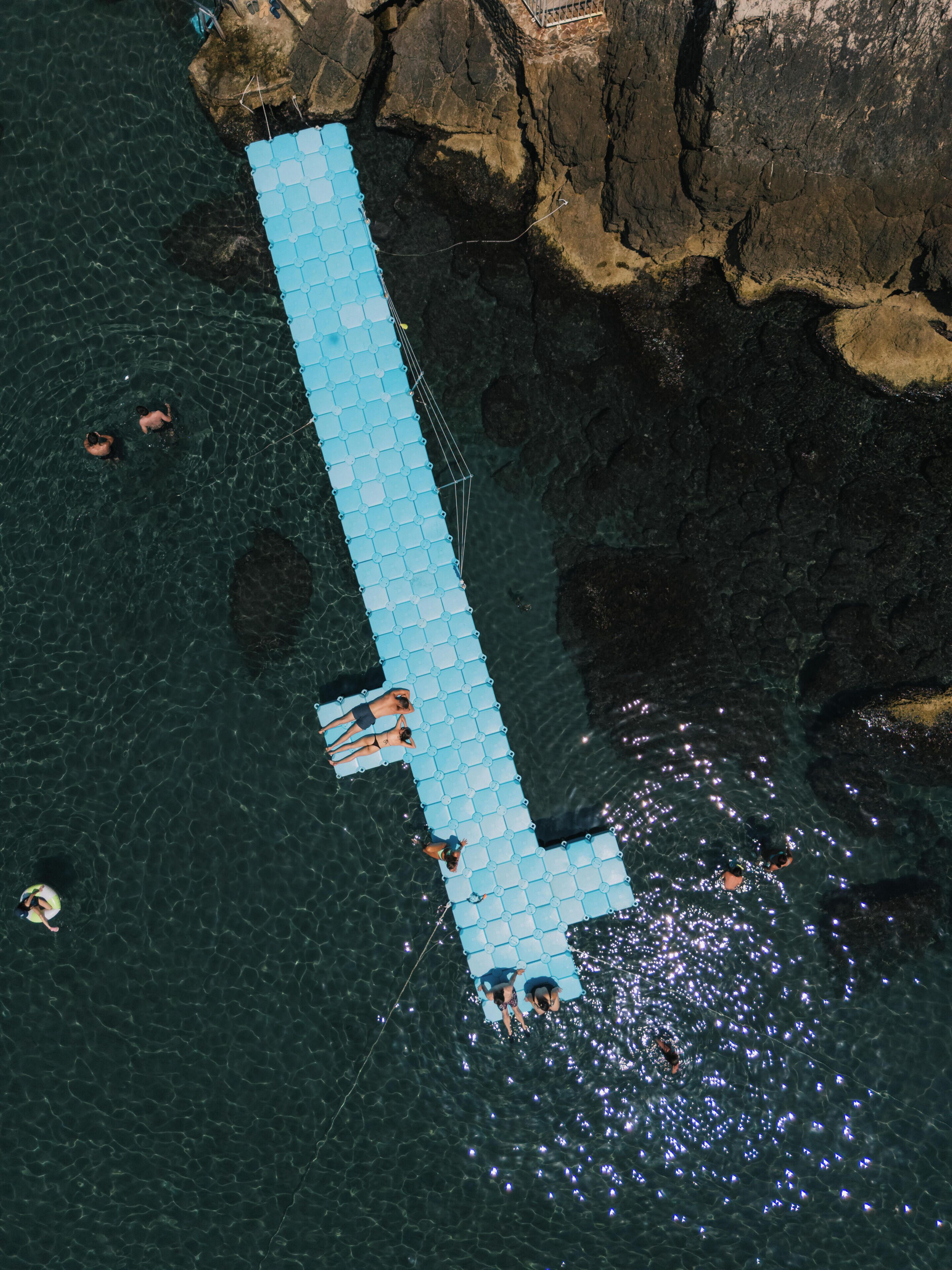 An aerial view of a dock extending into a body of water, surrounded by rocky terrain.