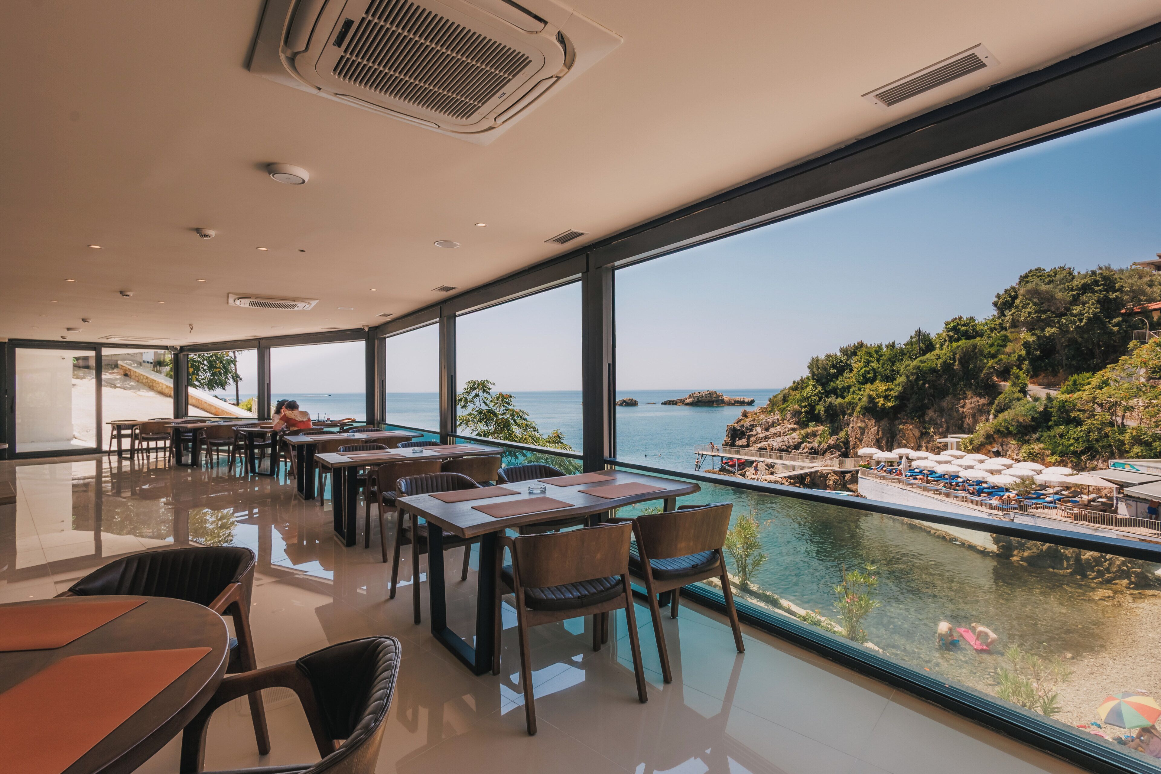 A modern dining area with large windows overlooking a coastal view.