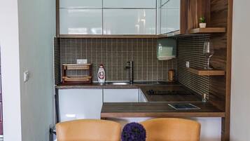 Una cucina compatta con zona pranzo, che include un tavolo e sedie in legno, un piccolo frigorifero e una parete rivestita di piastrelle.