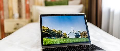 A laptop on a bed with a view of a house and trees on the screen.