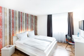 Une chambre d’hôtel moderne, dotée d’un grand lit, d’un bureau et d’une chaise.
