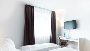 Una habitación de hotel con una cama, un escritorio con computadora y televisión.
