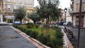 A city street with a sidewalk, benches, trees, and parked cars. - Luxury Catania (Catania)