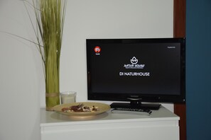 Un televisor sobre un pedestal blanco mostrando el texto “DI NATURHOUSE” con un logotipo.