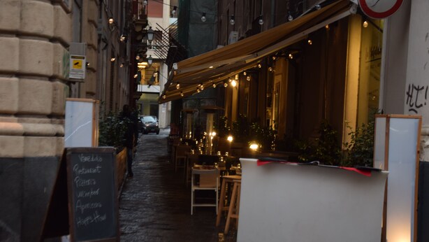 A narrow street with a restaurant featuring outdoor seating and string lights. - Luxury Catania (Catania)
